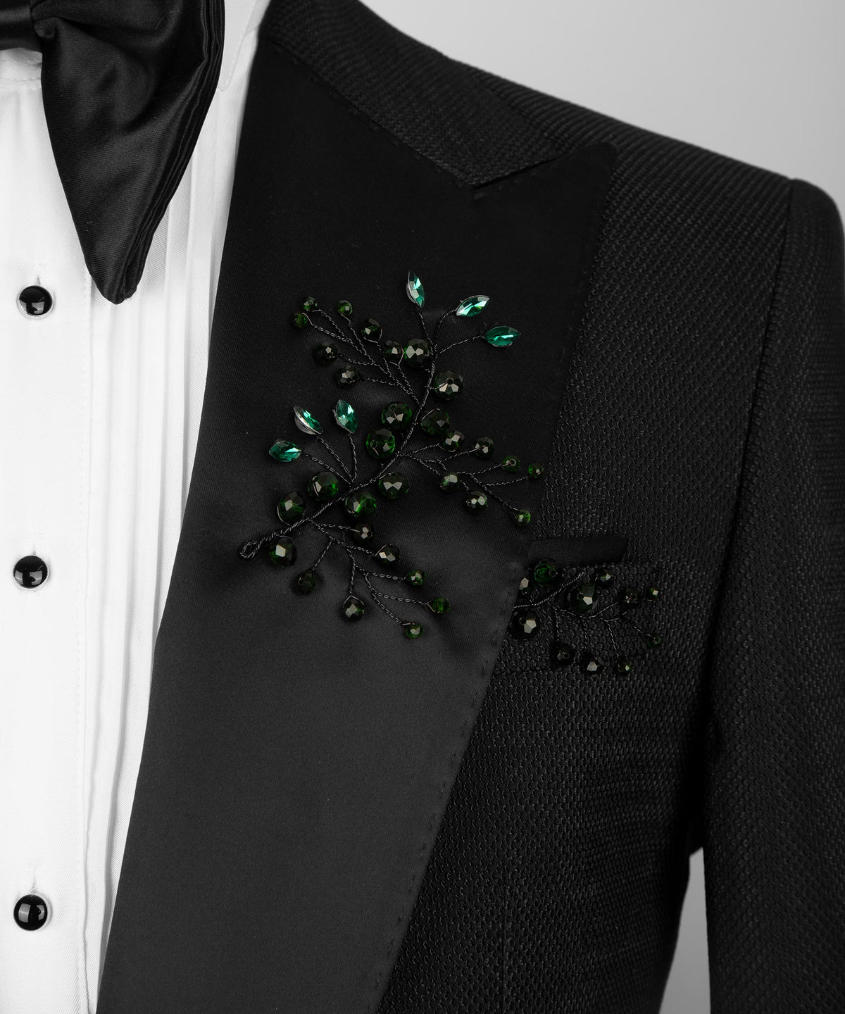 Close-up of black tuxedo breast pocket with green crystal floral embellishment