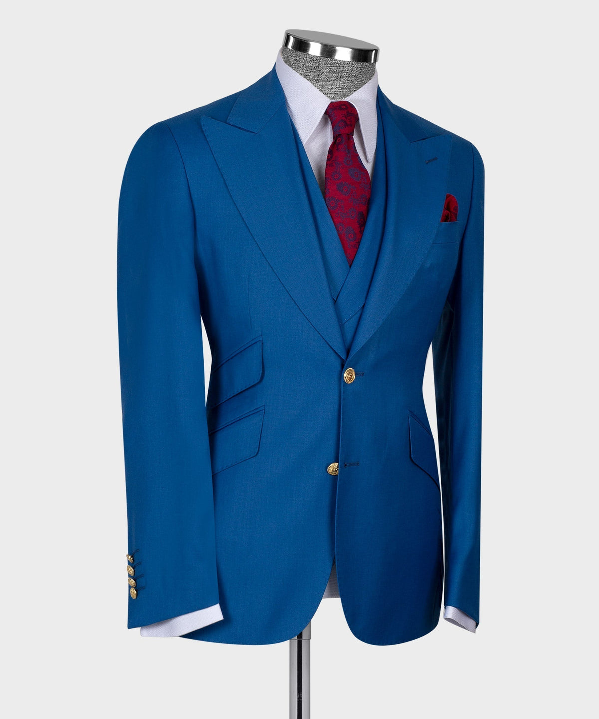 Blue three-piece suit with gold buttons, red patterned necktie, and welt pocket