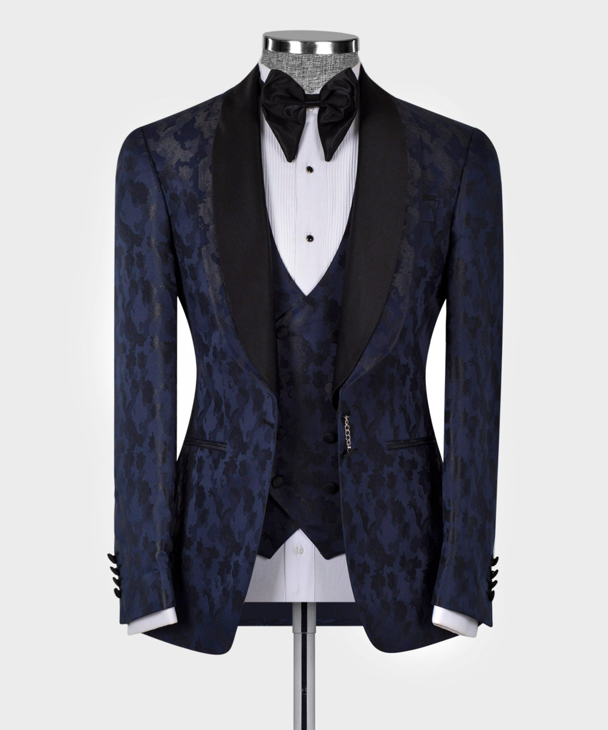 Navy tuxedo jacket with double lapels, black satin trim, bow tie, and patterned vest
