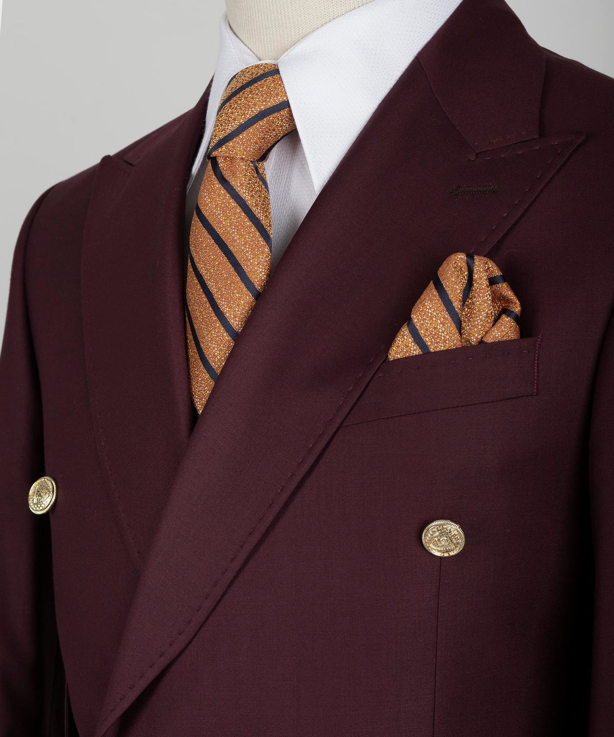 Burgundy blazer lapels with striped gold-accent tie and matching pocket square
