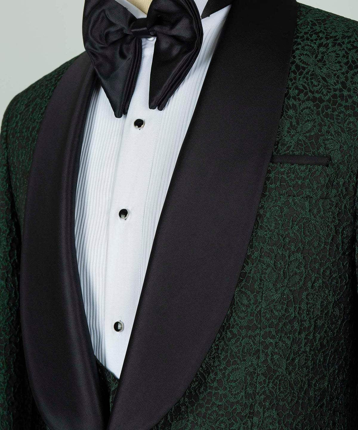 Black satin bow tie with white striped shirt and green patterned waistcoat