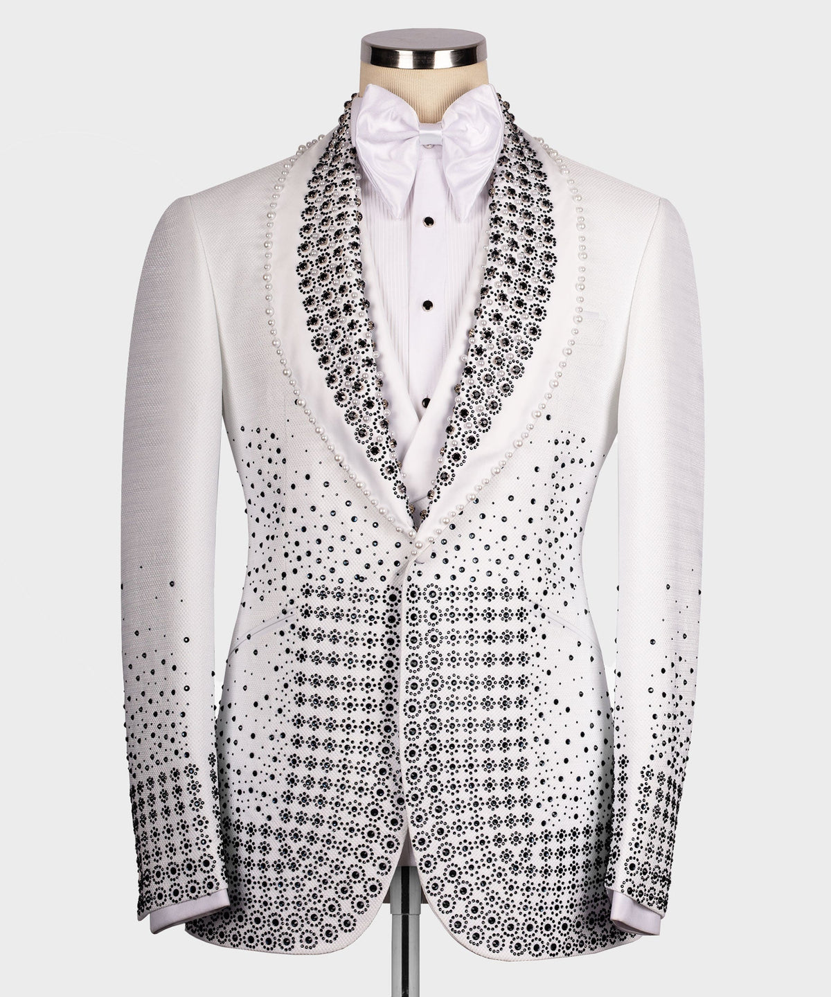 White tuxedo jacket with black gem-studded lapels, bow tie, and patterned front