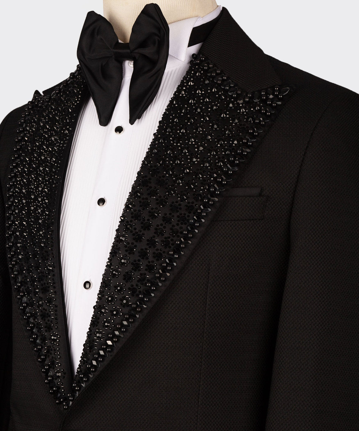 Close-up: black bow tie, white dress shirt, jeweled shawl lapel on black tuxedo