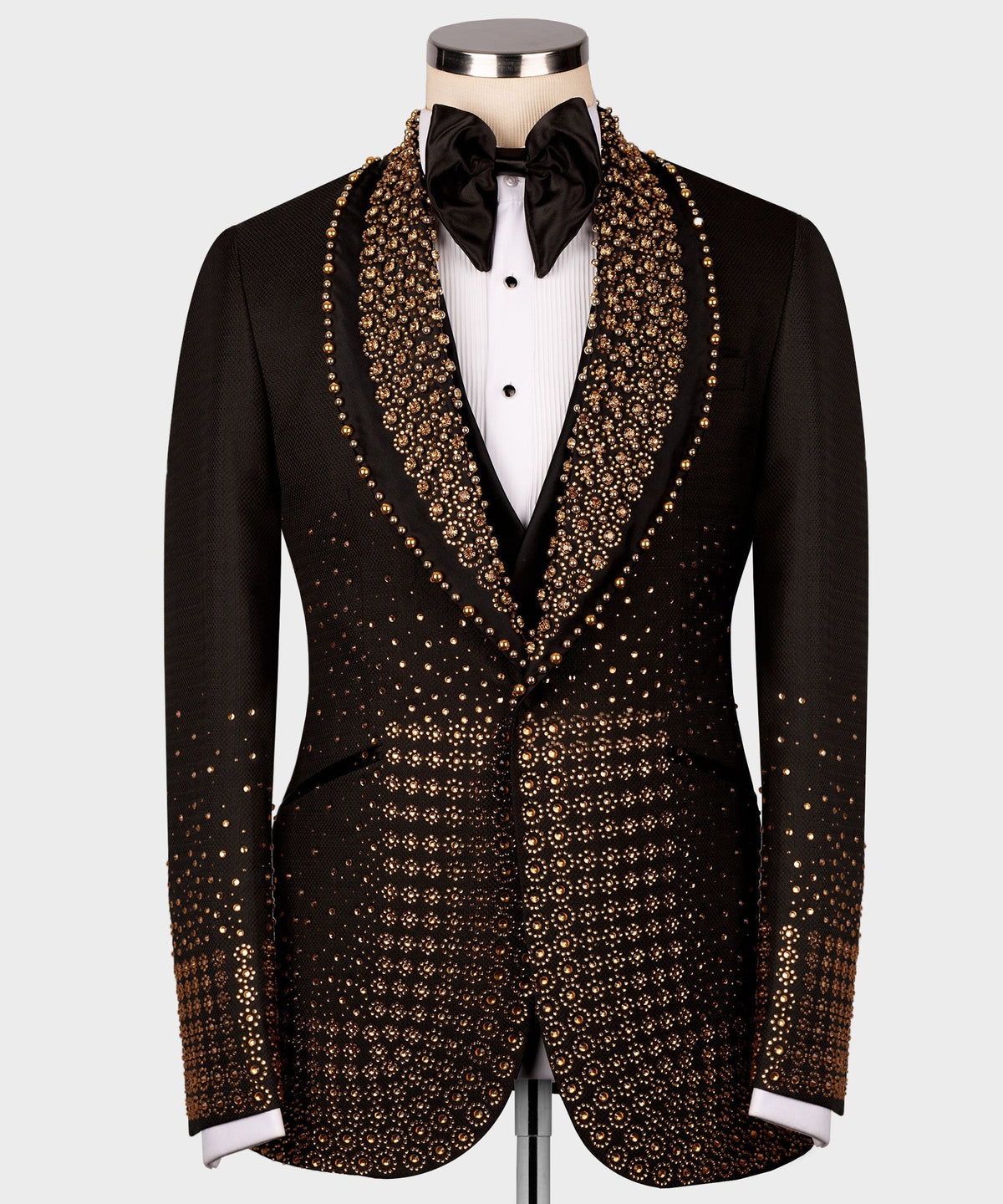 Black tuxedo jacket with dense gold gem-like trim on lapels and front panels, bow tie