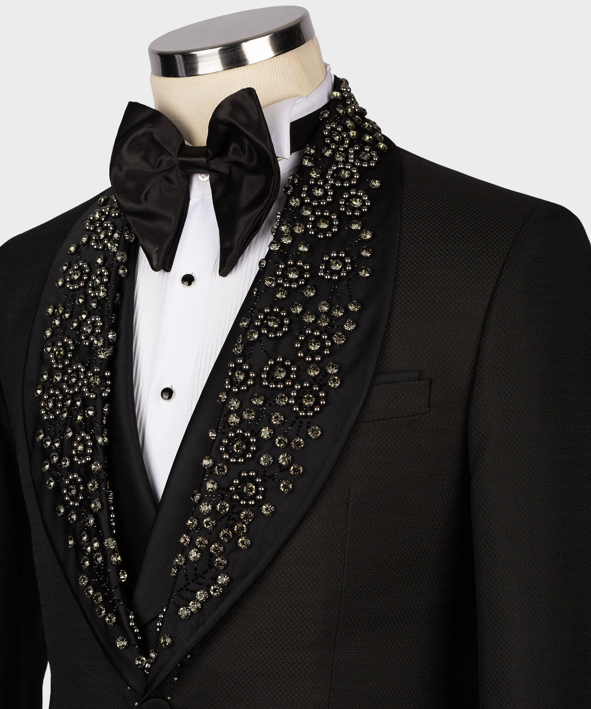 Close-up of black tuxedo lapels with gold-toned gem embellishments and satin bow tie