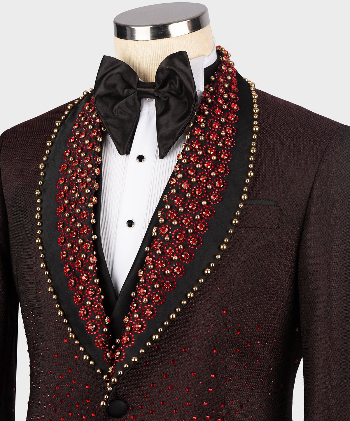 Close-up burgundy tuxedo lapels with red beadwork and gold trim, black bow tie