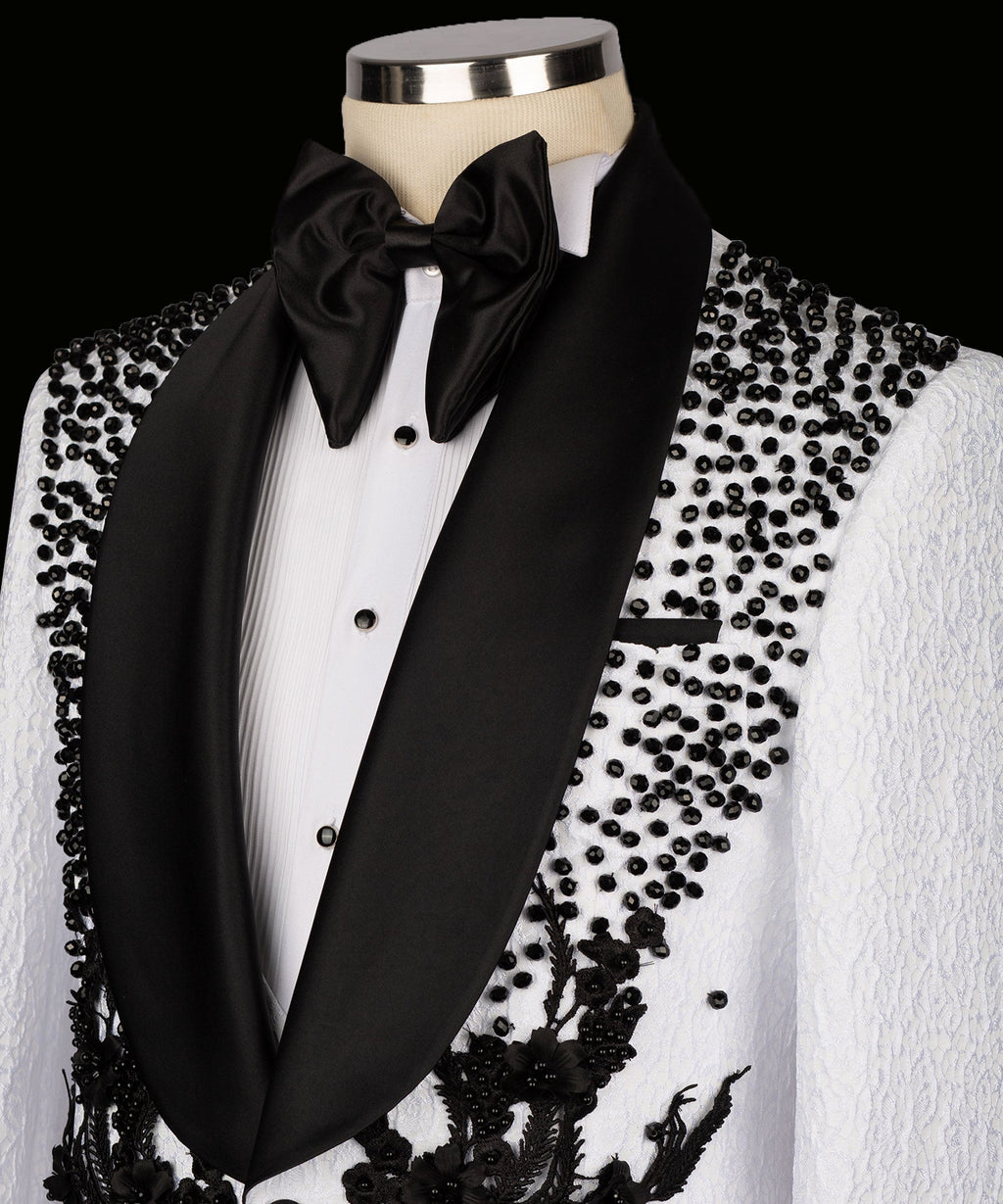 White tuxedo jacket with black satin lapels, bow tie, and floral embroidery on the chest