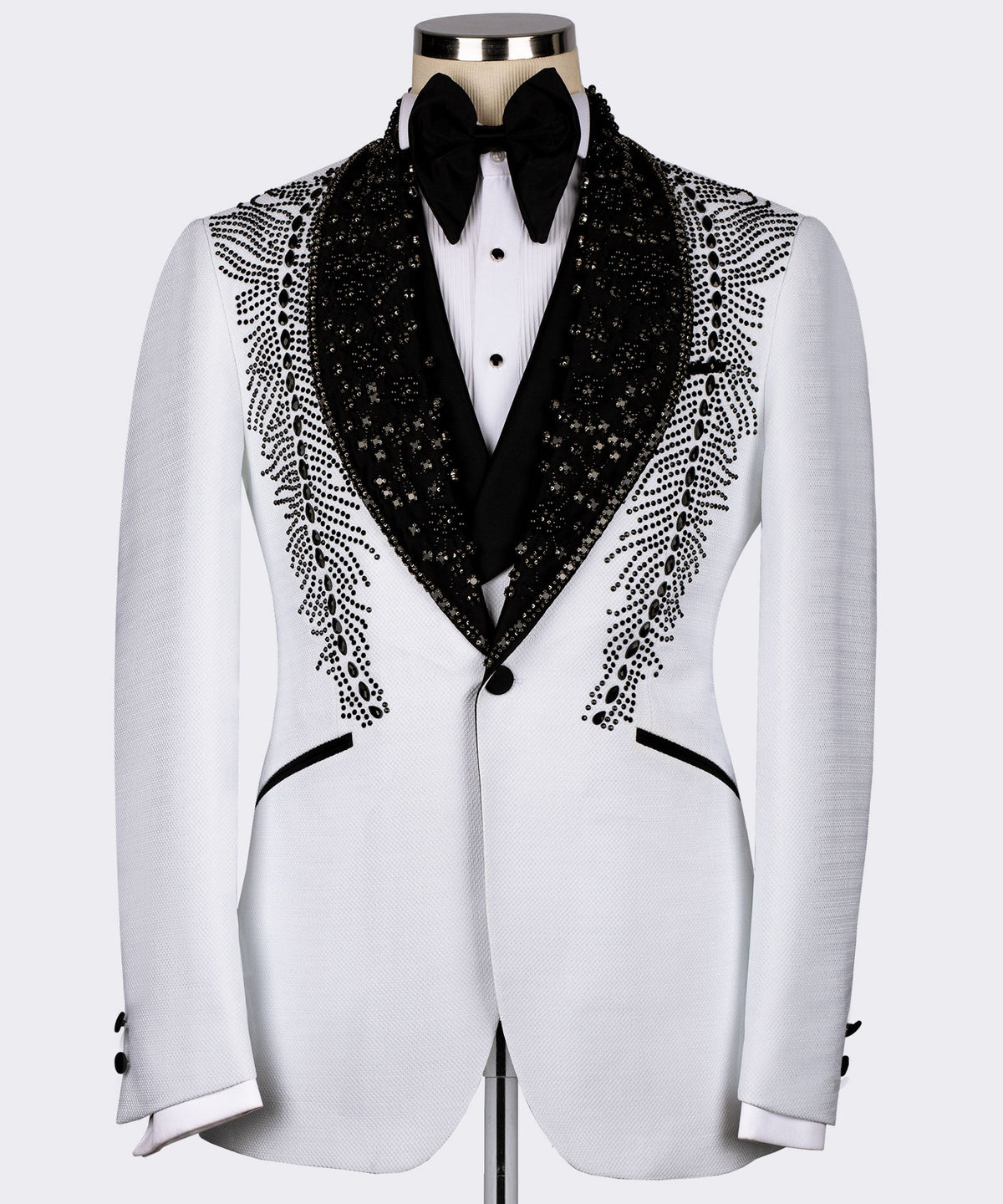 White tuxedo jacket with black embroidered lapels and feather-like stone pattern, bow tie