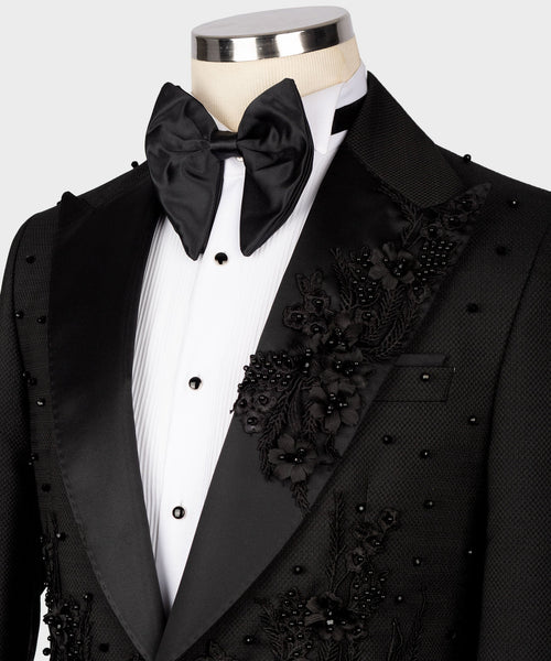 Black tuxedo set close-up: satin bow tie, vest with floral appliqué, pocket detail