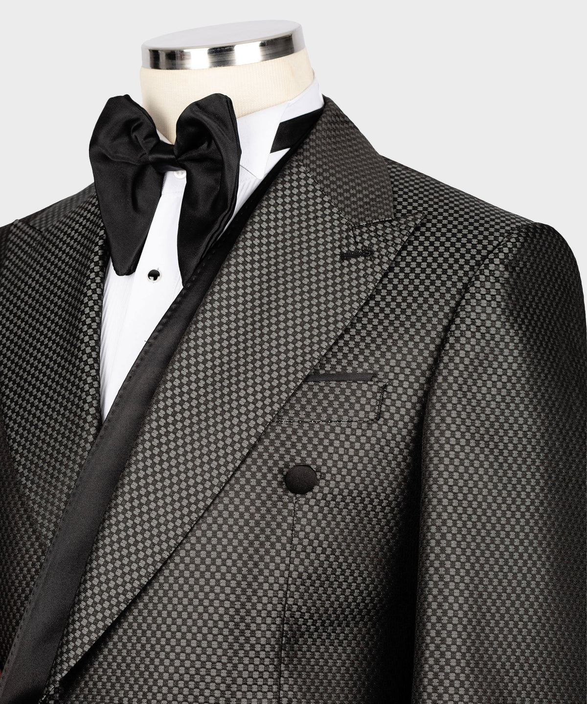Close-up: black satin bow at neck with black buttons on charcoal double-breasted jacket