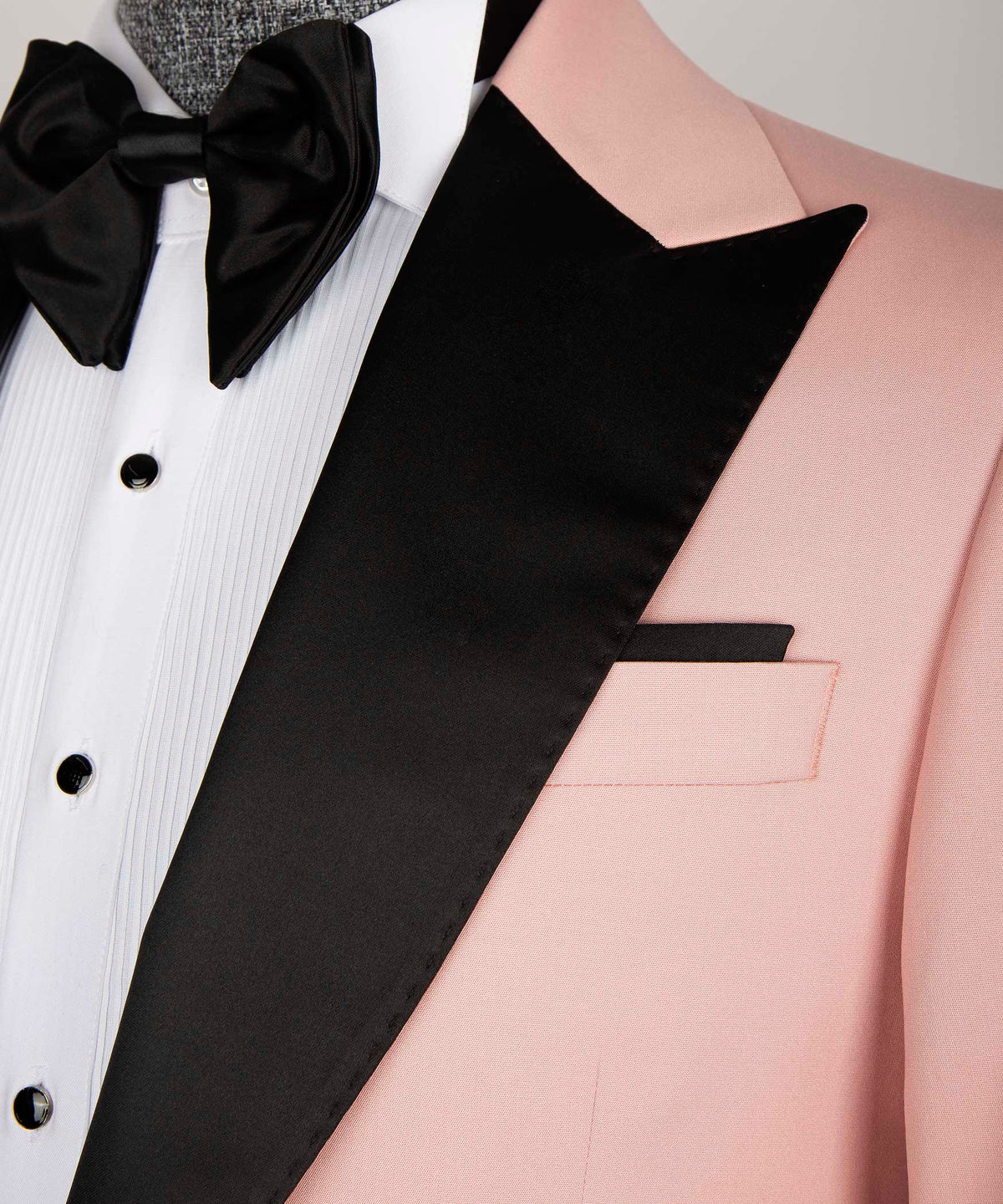 Close-up: black satin lapel edge, pink jacket pocket, and white shirt front