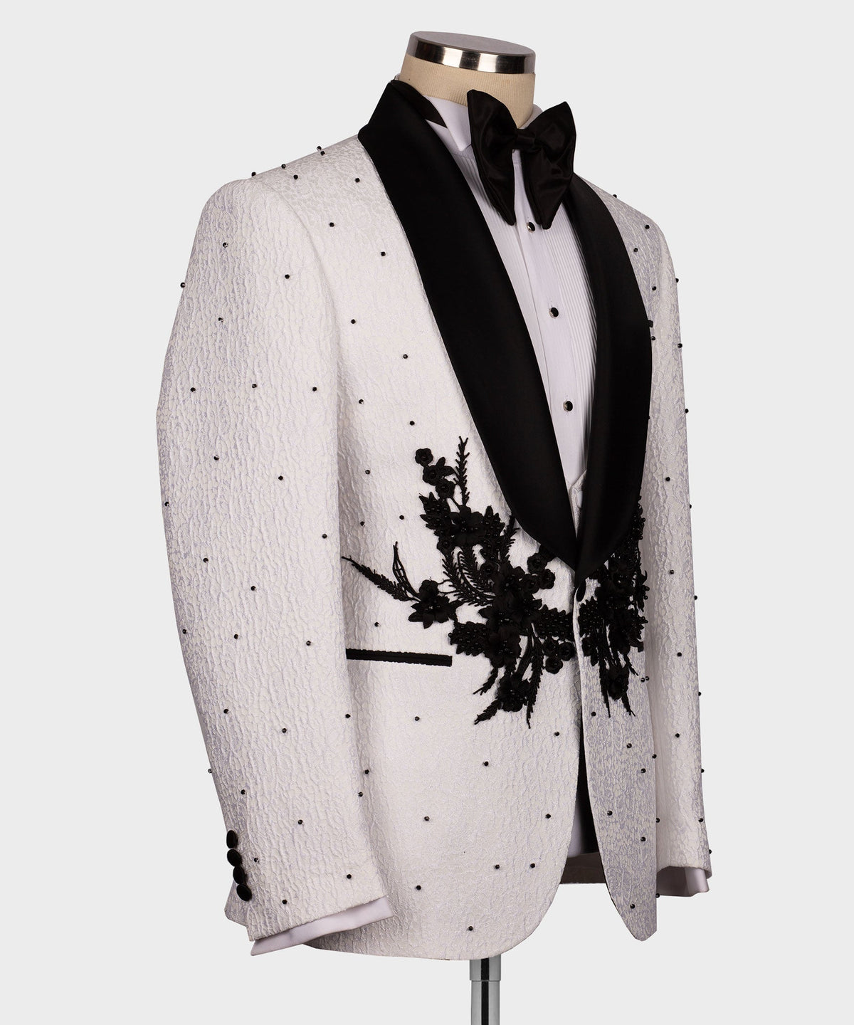 White tuxedo jacket side view with black lapels and large floral appliqué detail