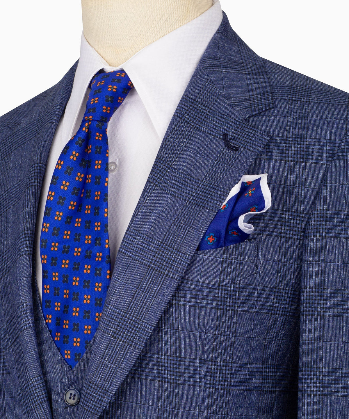 Close-up of blue plaid suit jacket lapel, pocket square, and matching patterned tie