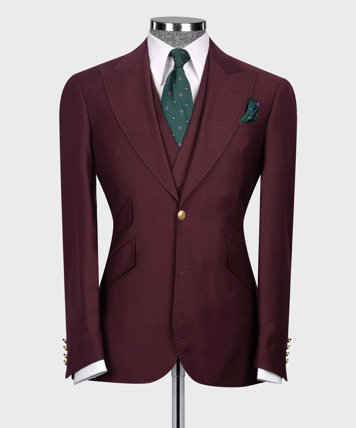 Burgundy suit blazer front with gold button closure, flap pockets, and green patterned tie.