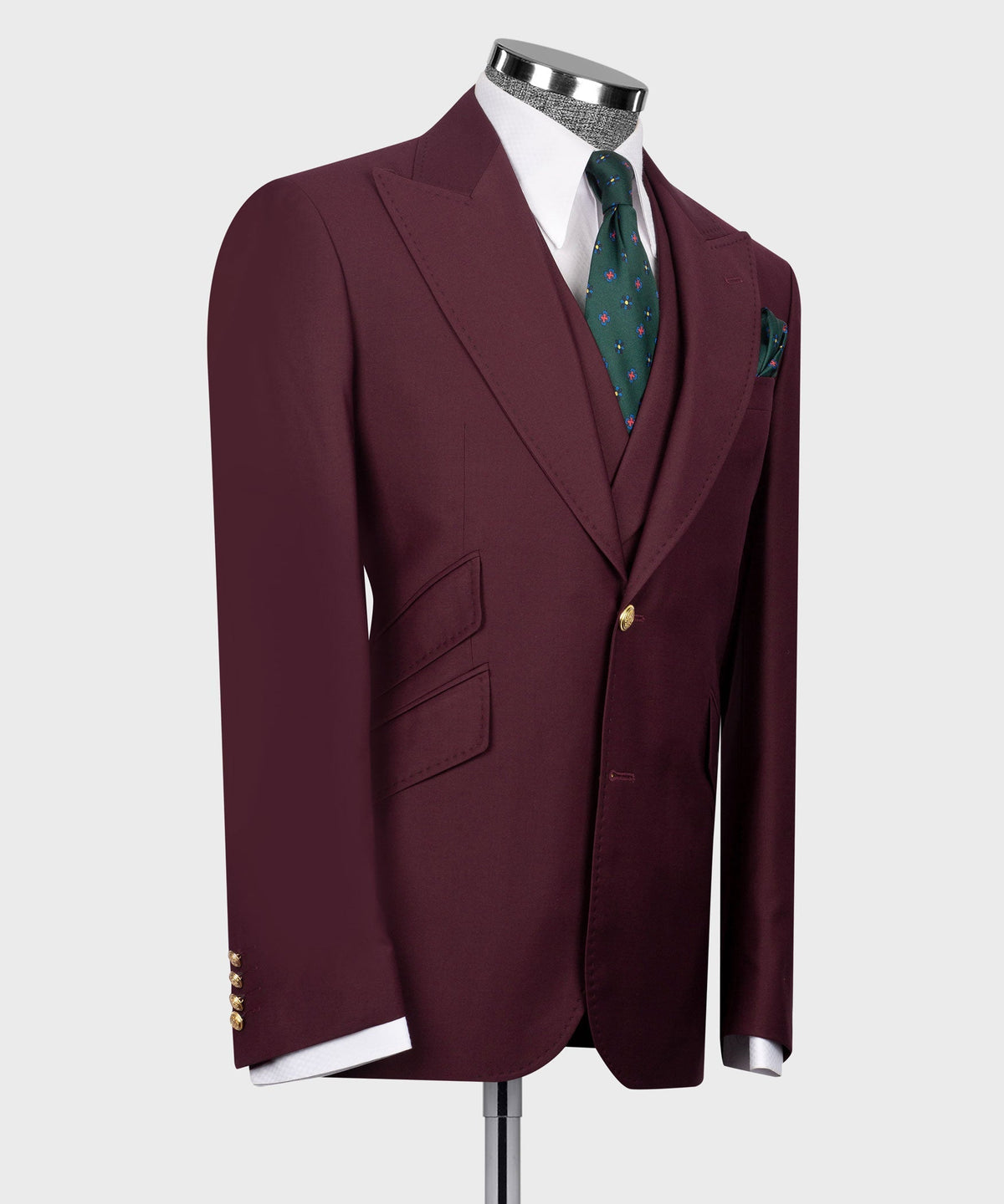 Burgundy suit blazer with notch lapel and gold buttons; green patterned tie and pocket square.