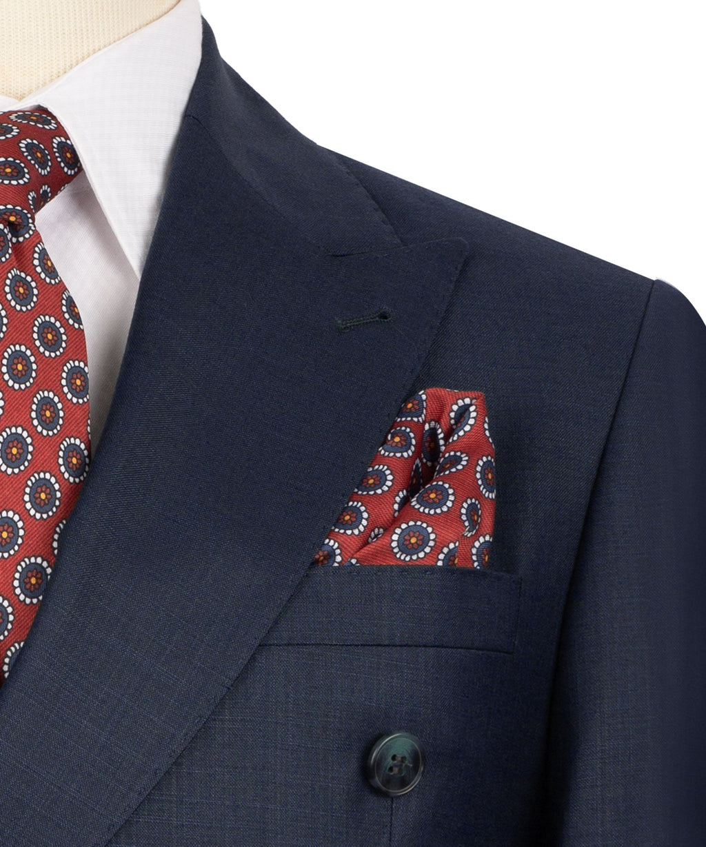 Navy suit jacket lapel with red patterned pocket square and matching patterned tie