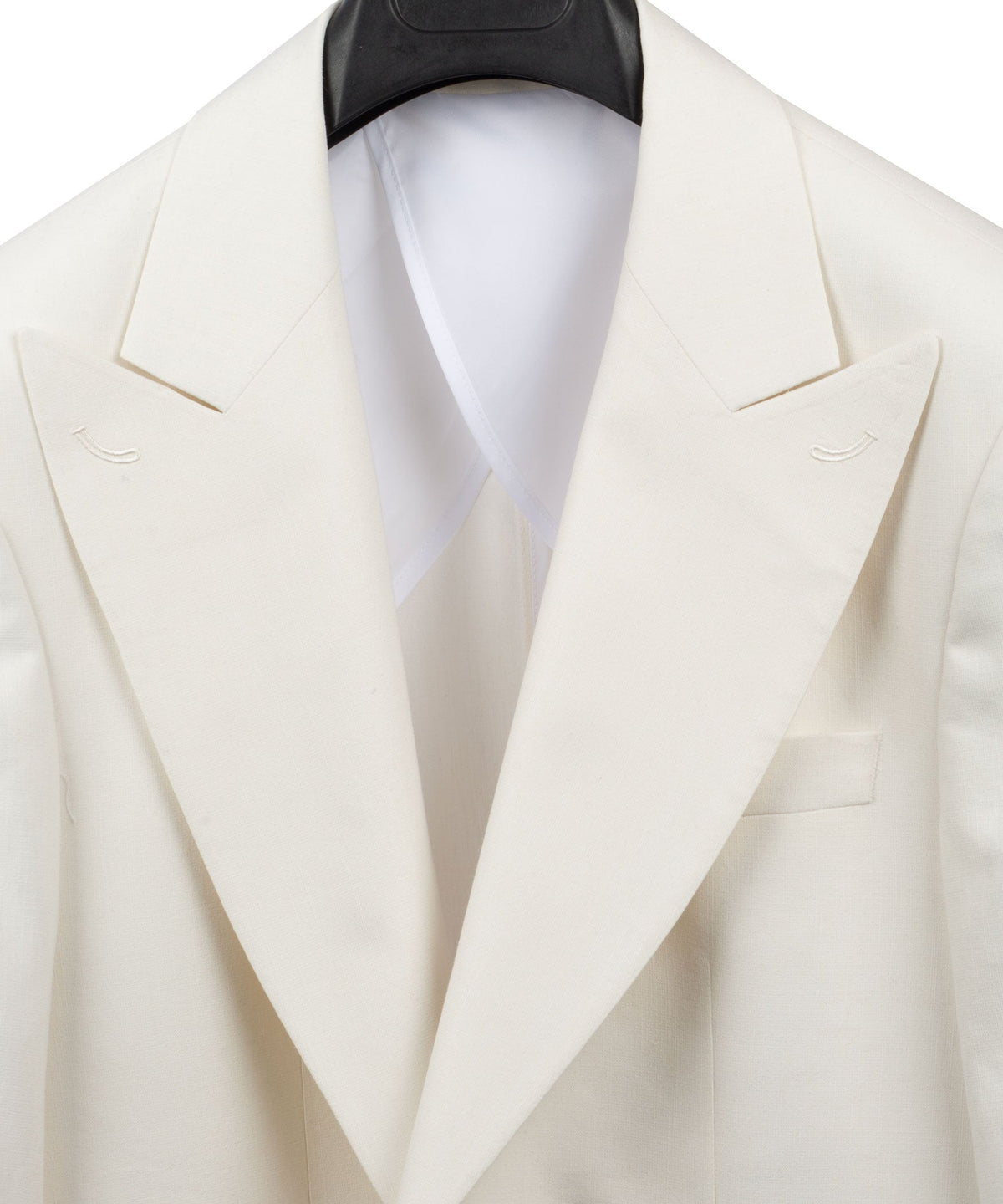 Cream linen blazer close-up of peaked lapels and welt pockets with white shirt collar