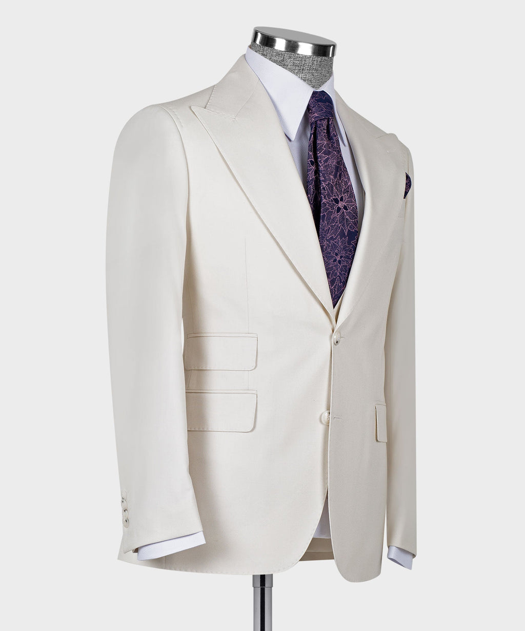 Side view of cream tailored blazer with matching vest, purple patterned tie and slim lapels