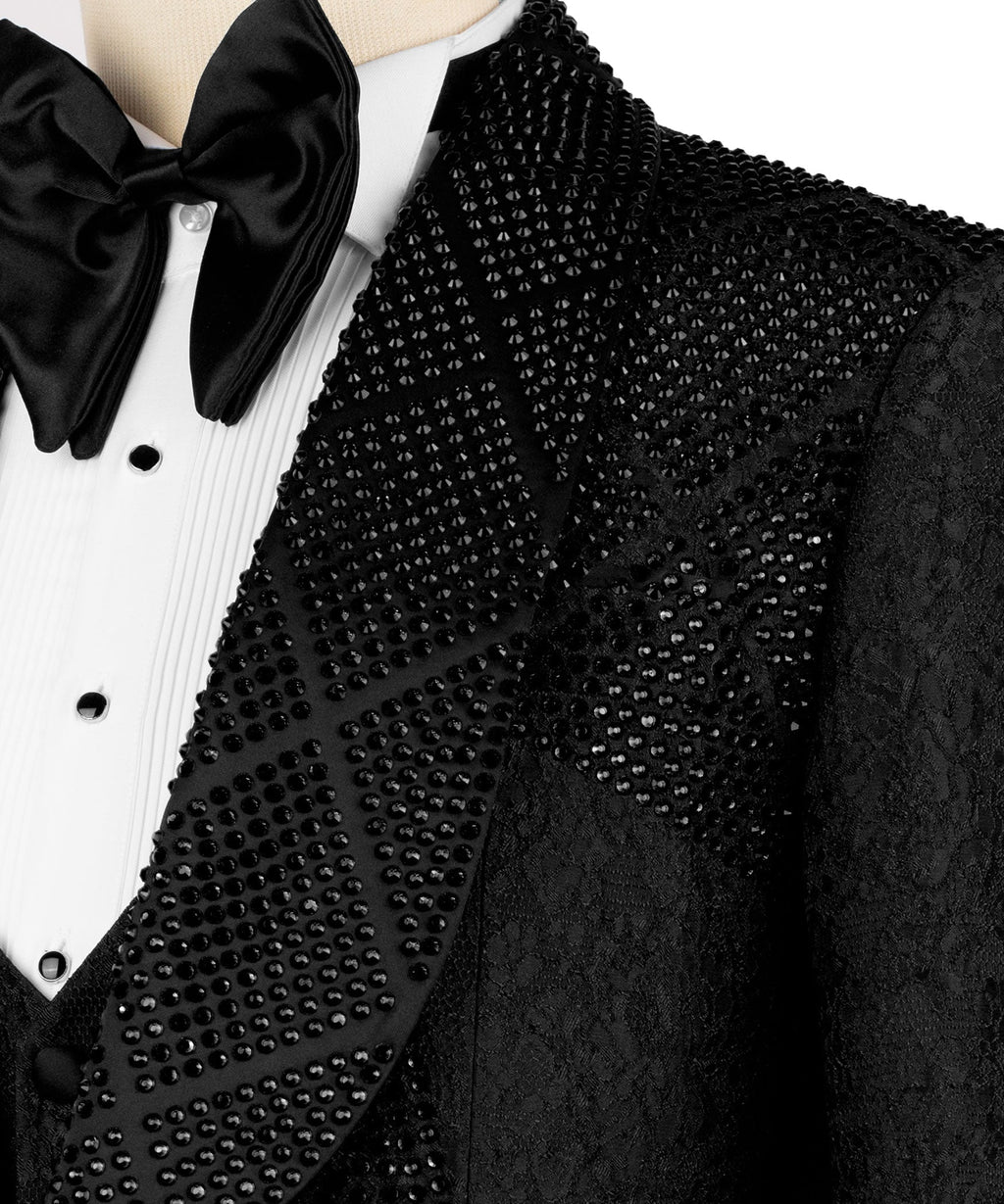 Close-up of black stone-embroidered lapel, satin bow tie, and white pleated shirt front