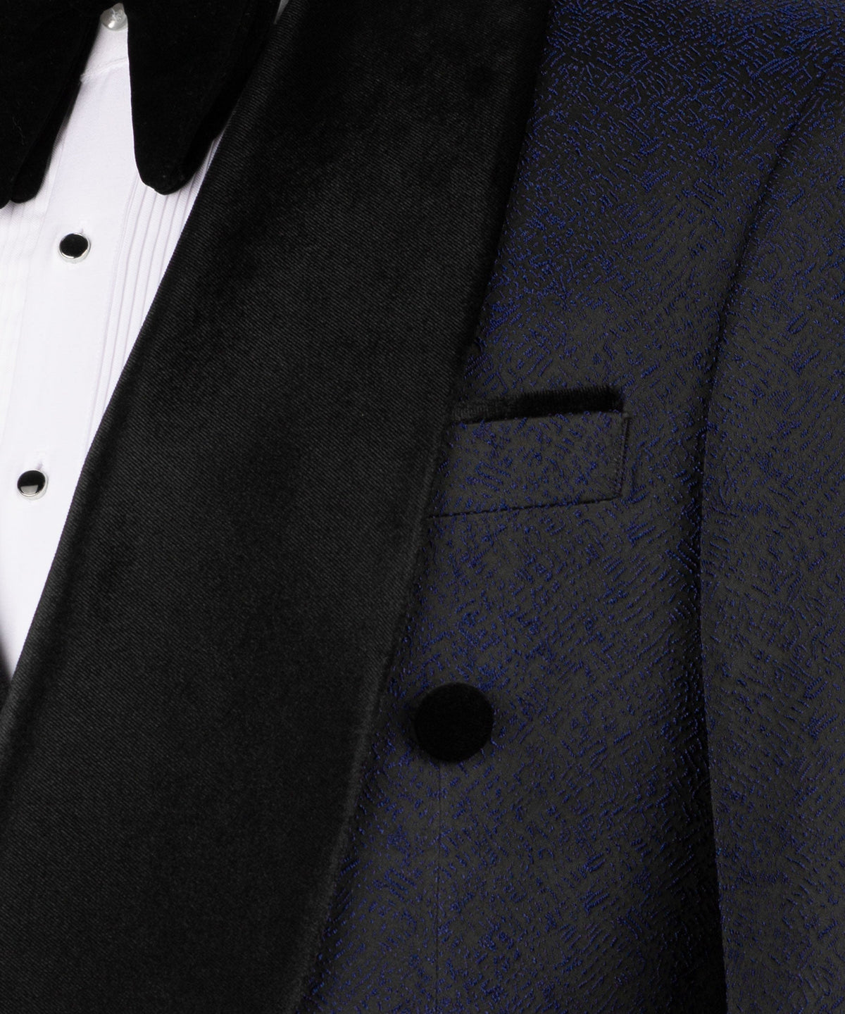 Close-up of black velvet tuxedo collar, lapel, and vest button on dark navy fabric