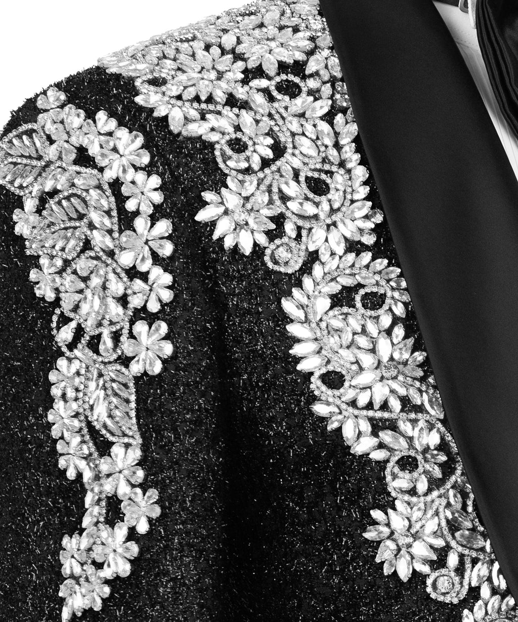 Close-up: silver stone flower and scrollwork embroidery on black jacket fabric