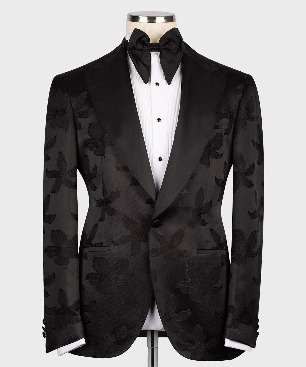 Black tuxedo jacket with pointed lapels over buttoned vest and bow tie